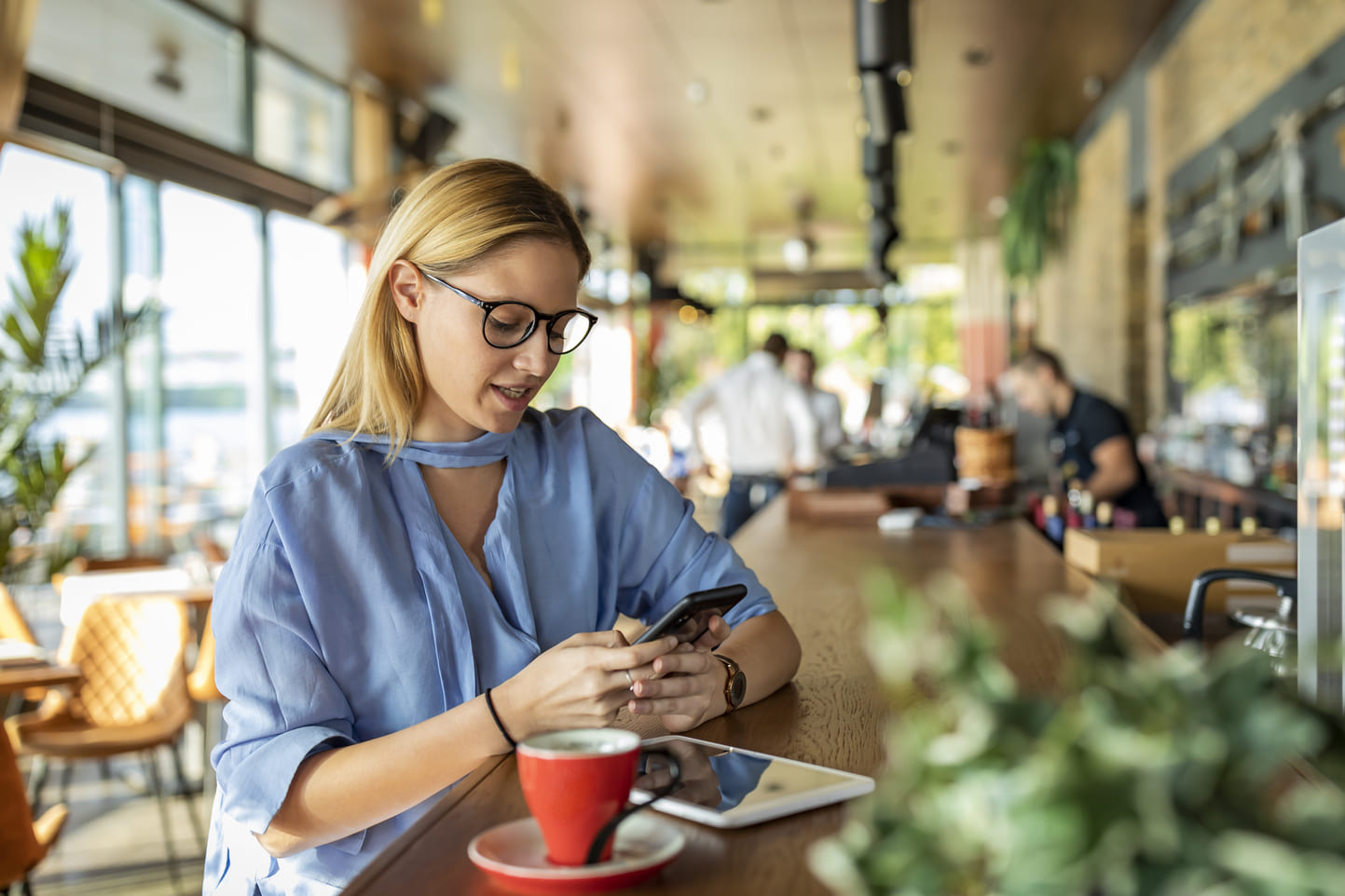 Woman working on her mobile devices at an outdoor café thanks to a high level of IT operational maturity