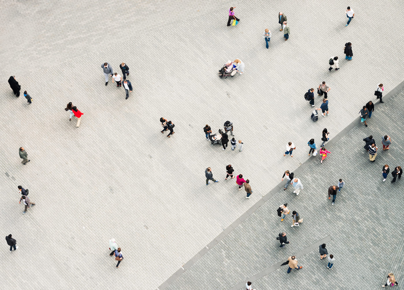 Ariel view looking down on a diverse scene of commuters walking in city setting.