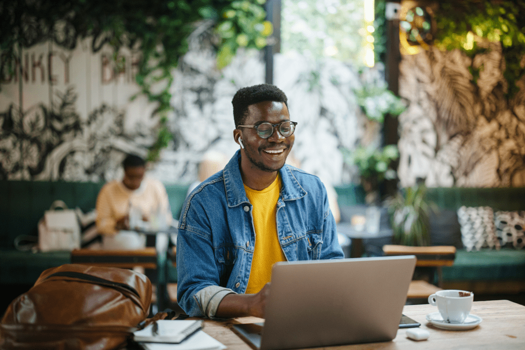 Man working on a laptop at an outdoor coffee cafe using IT helpdesk functionality in GoTo Connect unified communications as a service (UCaaS)