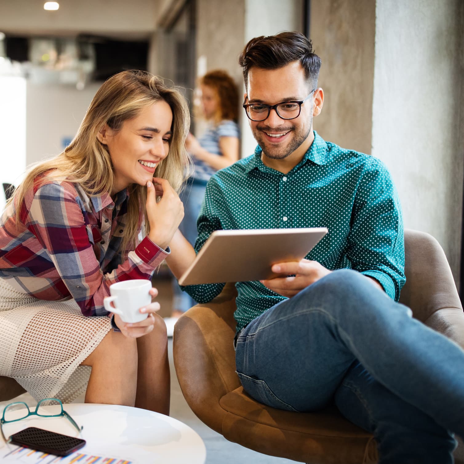 Coworkers in an office, working securely on a tablet with the help of GoTo Resolve's mobile device management software.